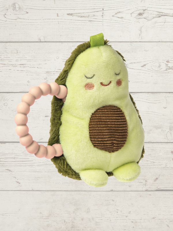 Plush avocado toy with a pink teething ring on a light wooden background