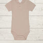 A rose organic cotton modal darcy rib tee bodysuit for babies, displayed on a wooden background.