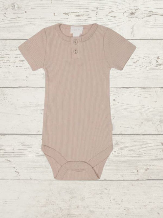 A rose organic cotton modal darcy rib tee bodysuit for babies, displayed on a wooden background.