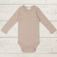 A long sleeve beige bodysuit for babies, presented on a wooden background.