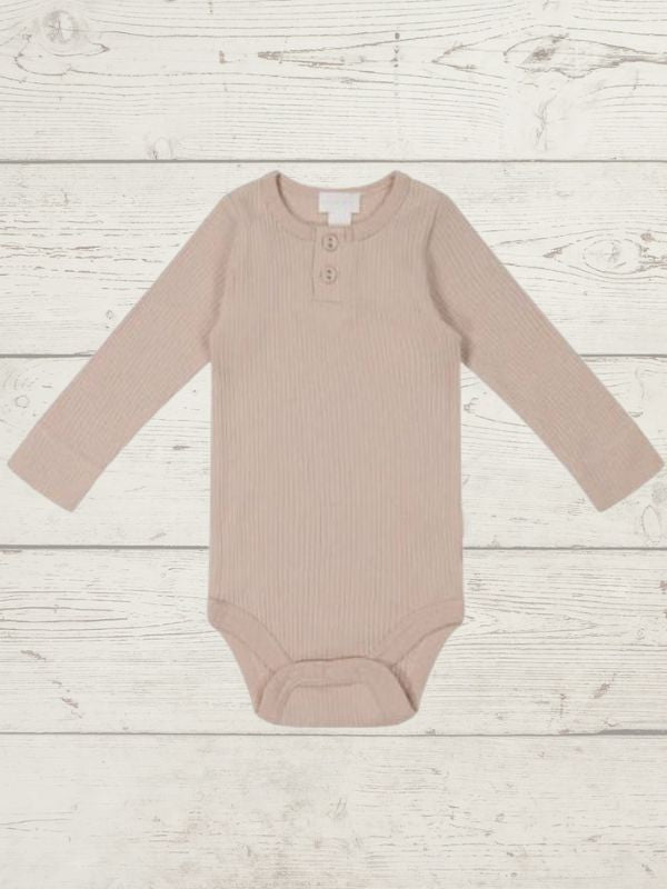 A long sleeve beige bodysuit for babies, presented on a wooden background.