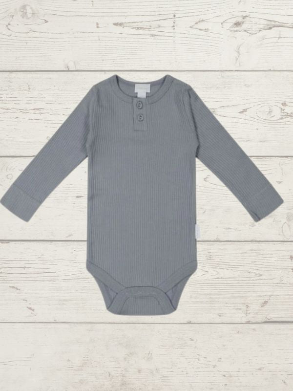 A long sleeve blue bodysuit for babies, presented on a wooden background.