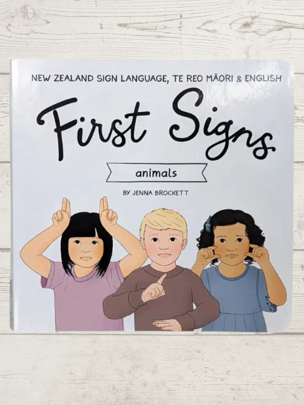 A hard cover book titled 'First Signs' with illustrations of three children using sign language. The book is part of the New Zealand Sign Language and English series.