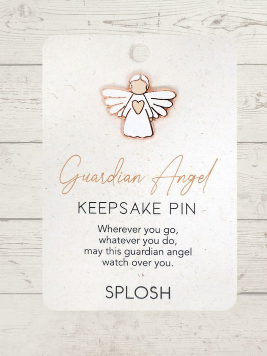 white guardian angel with a small pink heart keepsake pin on a card with a wooden background