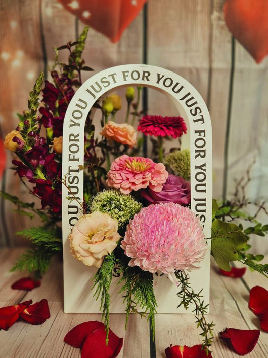 flowers displayed in a container with just for you written around handle
