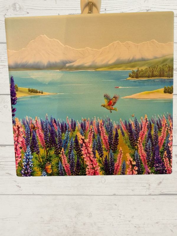 A ceramic tile featuring a vibrant Lake Tekapo scene with mountains, a sky, and a bird.