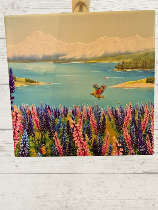 A ceramic tile featuring a vibrant Lake Tekapo scene with mountains, a sky, and a bird.