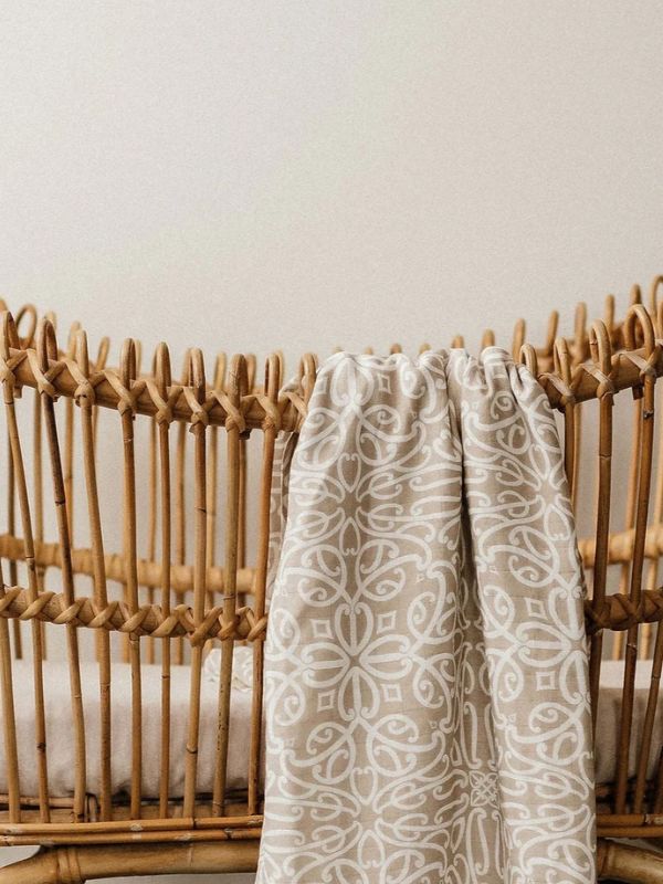 Patterned towel draped over a wicker basket against a neutral background