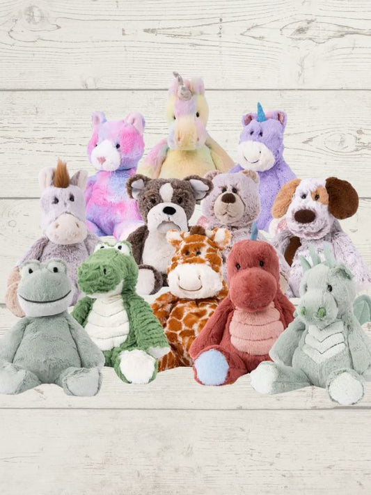 A collection of plush toy animals including a unicorn, pig, dog, horse, deer, and a dragon, arranged on a wooden surface.