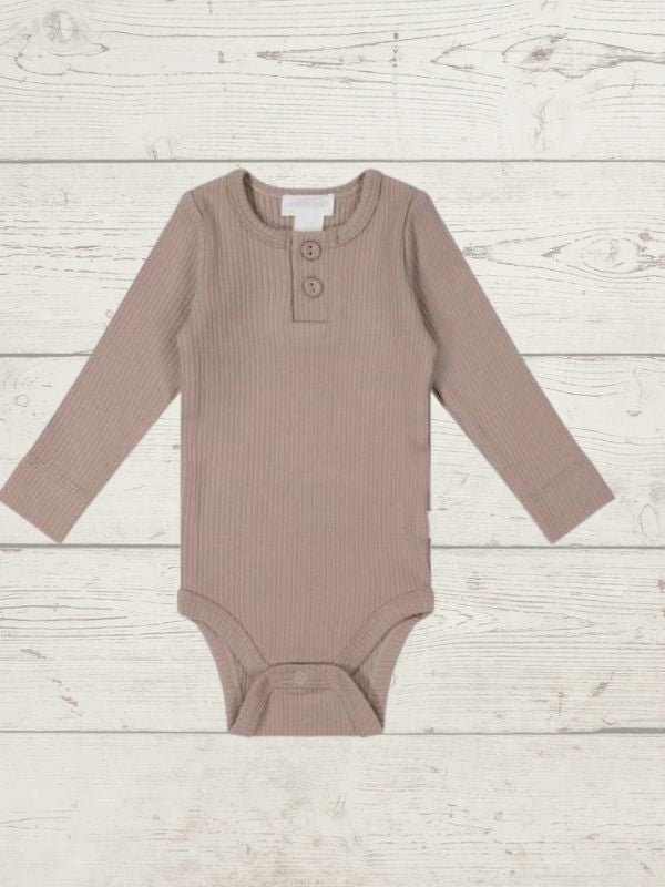 A long sleeve bodysuit for babies, in a beige color, presented against a wooden background.