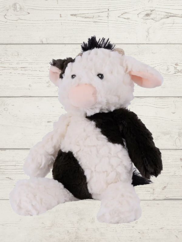 A plush toy resembling a cow with black and white fur, featuring embroidered eyes and a soft texture.