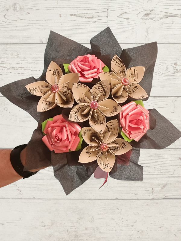 Bouquet of paper flowers with pink paper roses on a wooden background