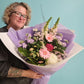 Person holding a bouquet of pastel themed flowers against a light blue background