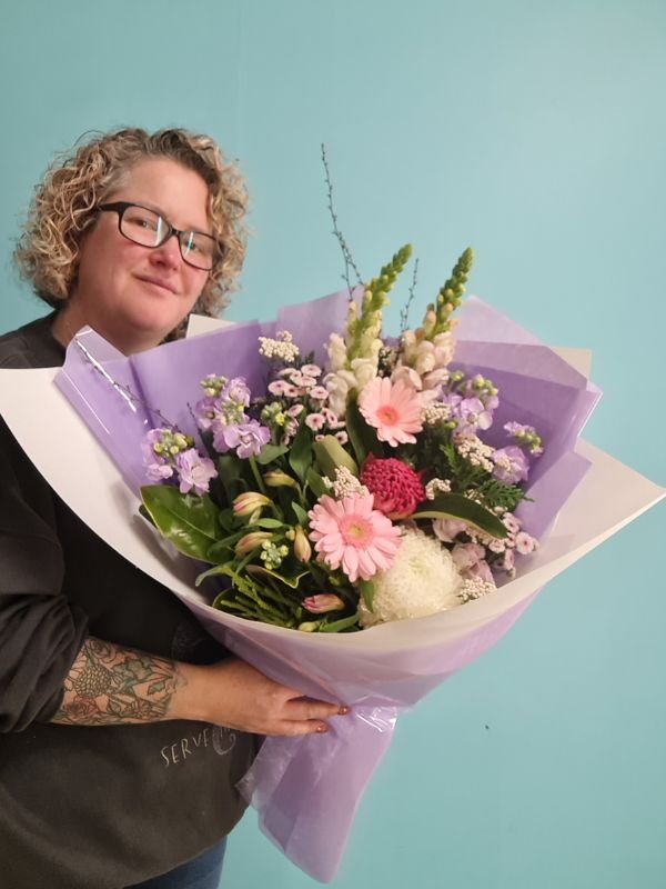 Person holding a bouquet of pastel themed flowers against a light blue background
