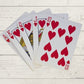 a spread of playing cards, ace, king, queen, jack and ten, all hearts on a wooden background