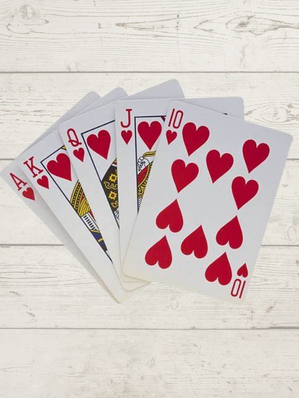 a spread of playing cards, ace, king, queen, jack and ten, all hearts on a wooden background
