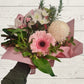 posy box of flowers with pink and white flowers on a light wooden background