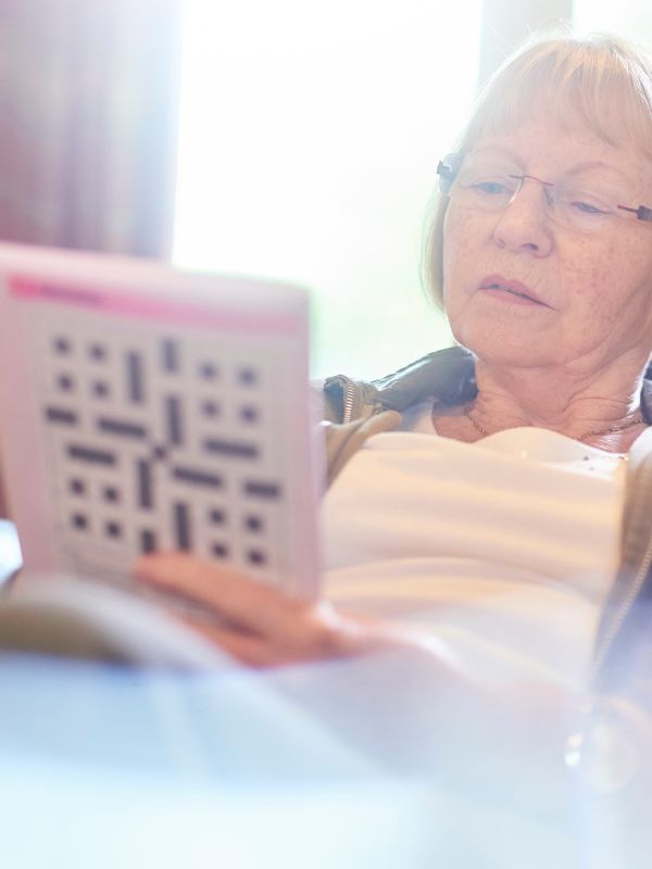 lady in a white tshirt and glasses looking at a crossword book