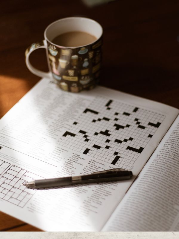 crossword book with a coffee cup and pen on a table