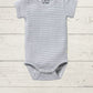 A gray short-sleeve rib bodysuit for babies, with a round neckline and side snap opening, displayed on a wooden background.