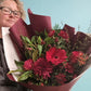Person holding a bouquet of red flowers against a light blue background