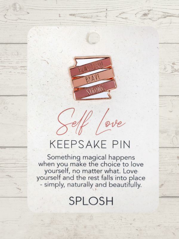 embossed keepsake pin with Self Love written on it on a wooden surface