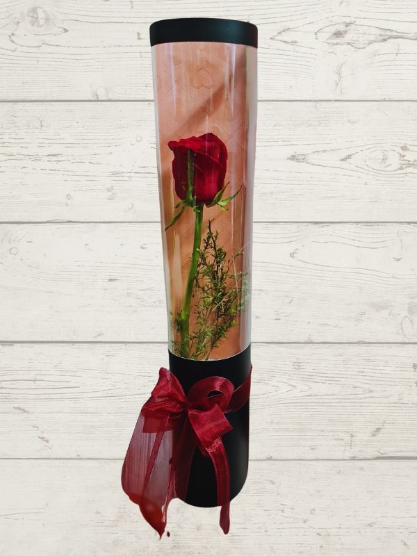 a red rose inside a black cylinder with ribbon