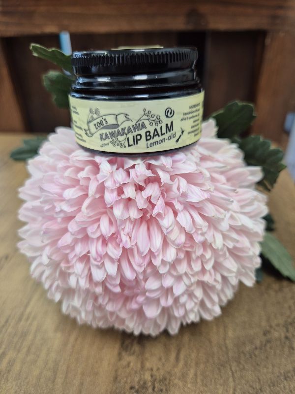 black pottle with a yellow label of Lip Balm on a pink floral on a wooden surfaace