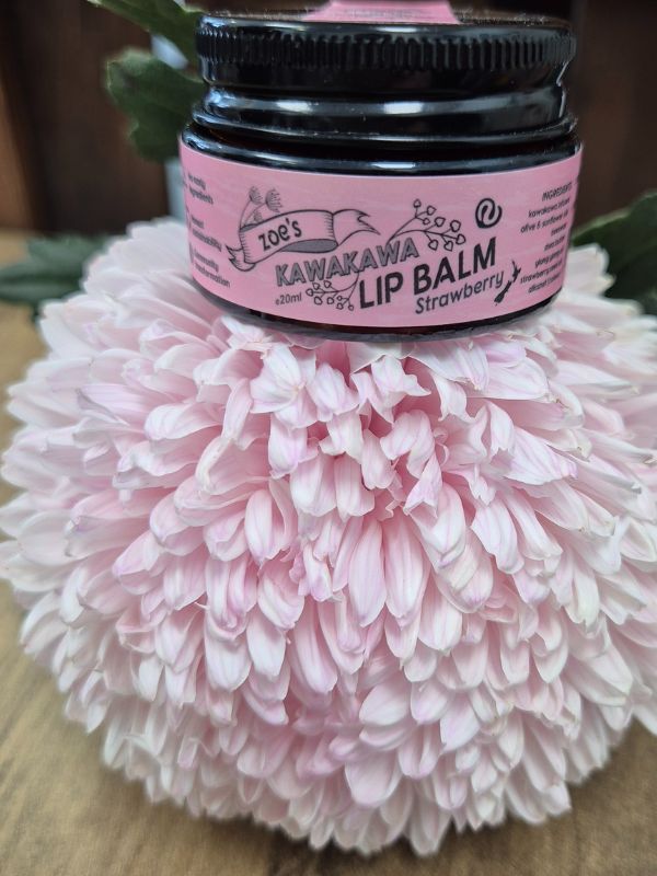 pottle with pink label of Lip Balm on a pink floral design on a wooden surface