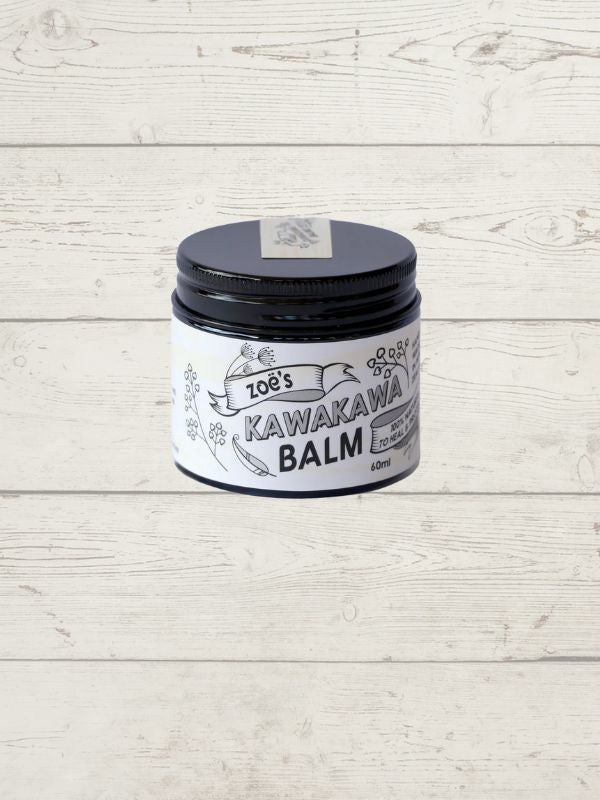 pottle of kawakawa balm by Zoes in a black container with a white label on a wooden background