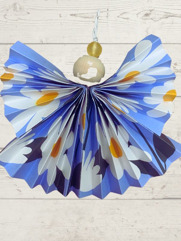 Decorative paper fan with blue, white, and orange pattern on a wooden surface