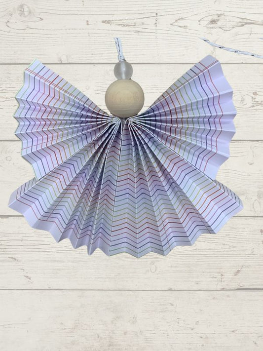 Decorative angel ornament with iridescent wings and a gray bead on a light wooden surface