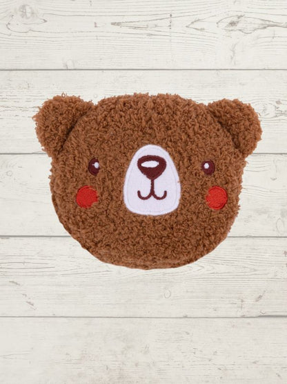Brown teddy bear-shaped cushion on a light wooden surface