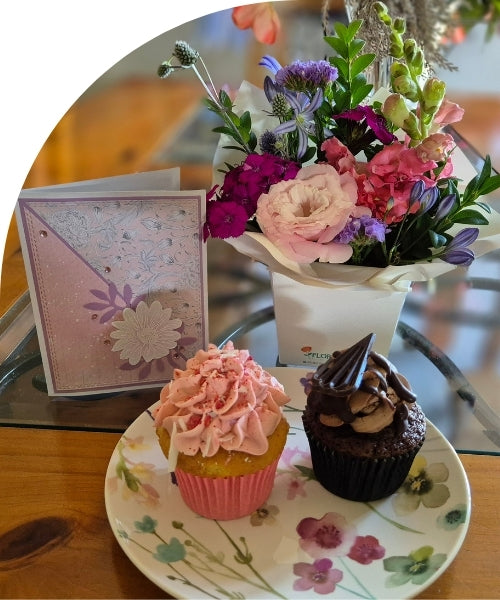 A small posy of flowers with two cupcakes and a handmade card. 