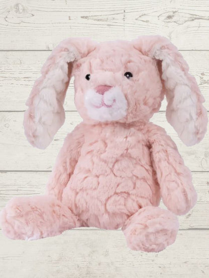 Two soft toy bunnies with beige and white coloring, sitting on a wooden surface. One bunny is plush and the other is a stuffed toy, both with embroidered eyes and a textured surface.