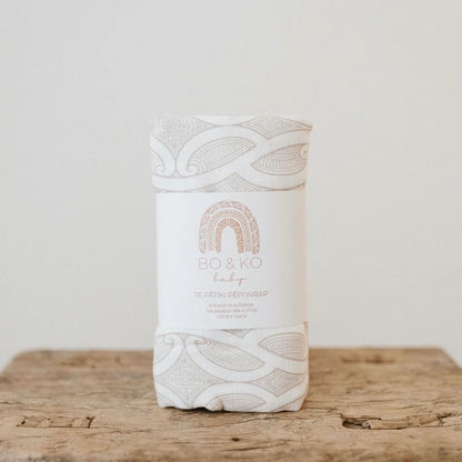 White baby wrap with intricate patterns on a wooden surface