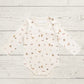Baby bodysuit with animal prints on a light wooden surface