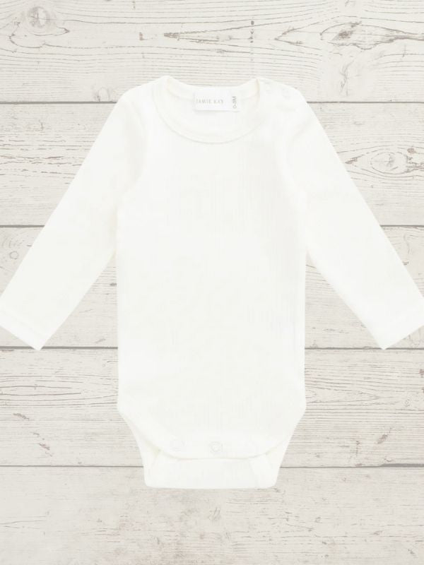 White long sleeve bodysuit on a light wooden surface