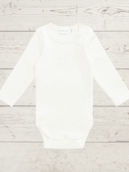 White long sleeve bodysuit on a light wooden surface