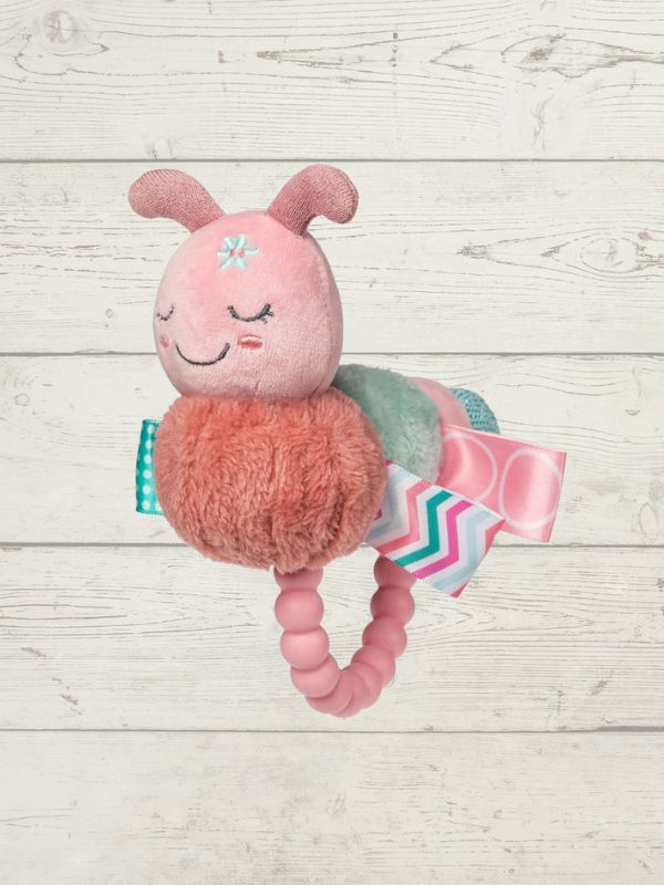 Pink plush toy with a teething ring on a wooden surface
