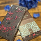 A chocolate bar with decorative toppings, placed on a wooden surface next to a flower, with the brand 'Chocolate Traders' visible on the packaging.