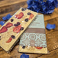A chocolate bar with decorative toppings, placed on a wooden surface next to a flower, with the brand 'Chocolate Traders' visible on the packaging.