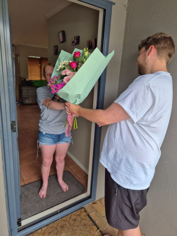 A person handing another person a bouquet of flowers in an open doorway