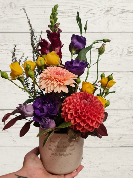 flowers in an array of colours in a pot with wording friends are those who make you laugh louder and smile brighter. 