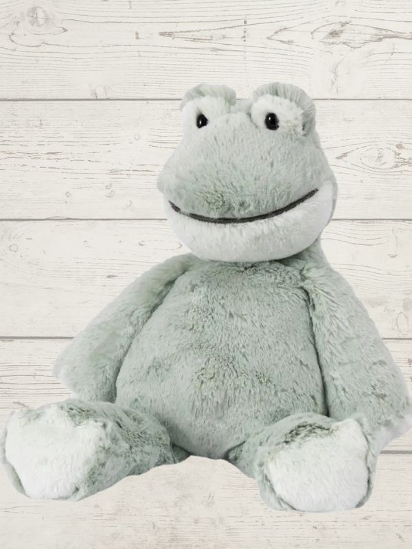 A gray plush toy resembling a frog with embroidered details on the face and a soft body, placed against a wooden background.