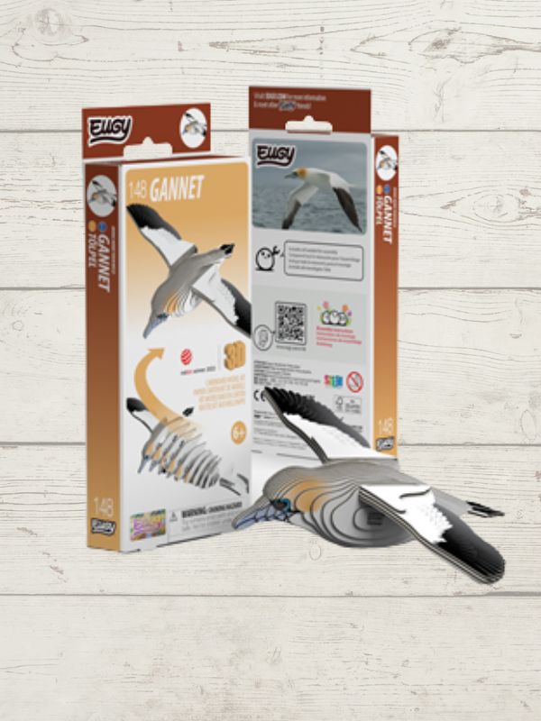 A 1/4 scale plastic model kit of a gannet bird, shown with its retail packaging on a light wood background. The kit includes a detailed bird model and an instruction booklet.