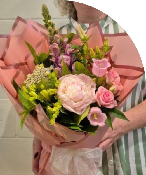 A bouquet of pink flowers being held by a person. 
