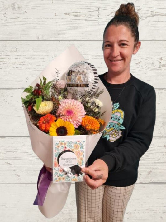A person holding a bright fresh flowers bouquet with a balloon and a handmade card. 