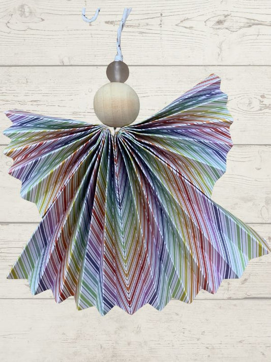 Colorful striped butterfly decoration with a wooden bead on a light wooden background