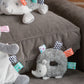 Plush hedgehog toy with colorful tags on a grey couch
